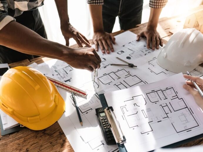 Construction professionals reviewing architectural blueprints on a wooden table, illustrating Bayside Builders Group's expertise in home remodeling and renovation projects in the Bay Area.
