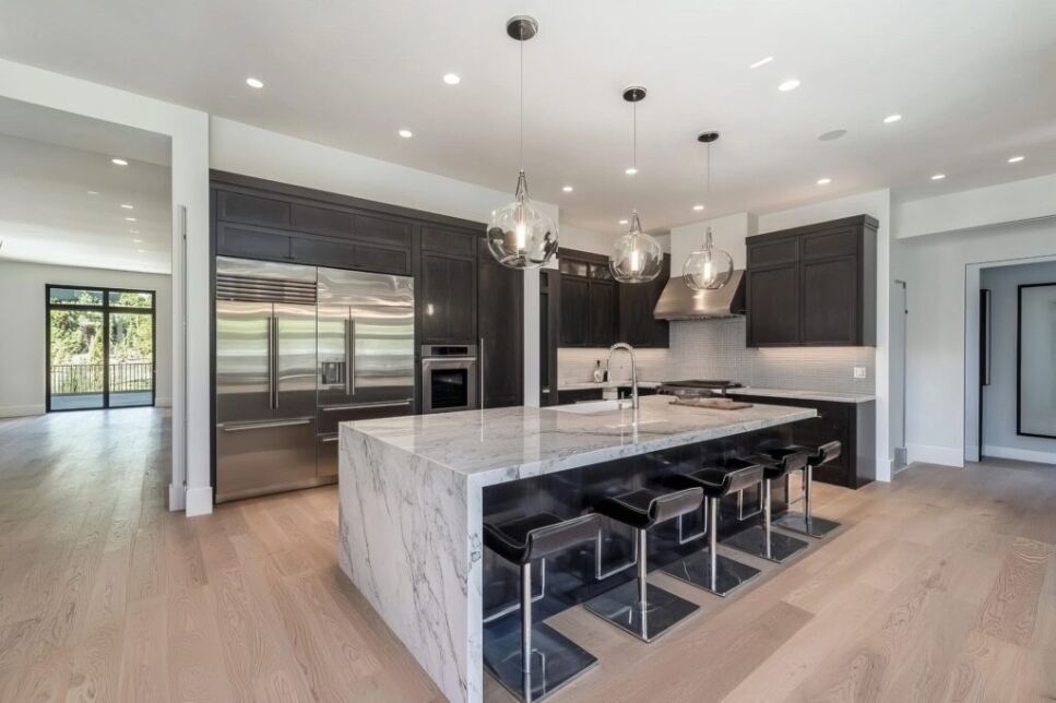 A modern kitchen renovation showcasing sleek black cabinetry, stainless steel appliances, and a marble island, reflecting Bayside Builders Group's expertise in high-end kitchen remodels in the Bay Area.